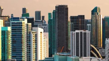 Alacakaranlıkta sinematik Miami ufuk çizgisi manzarası akşam güneşinin altında parlayan yüksek binalar şehir ışıklarıyla şehir mimarisini harmanlıyor. Şehir manzarasını ve Florida 'da gün batımını araştırın. 4k görüntü