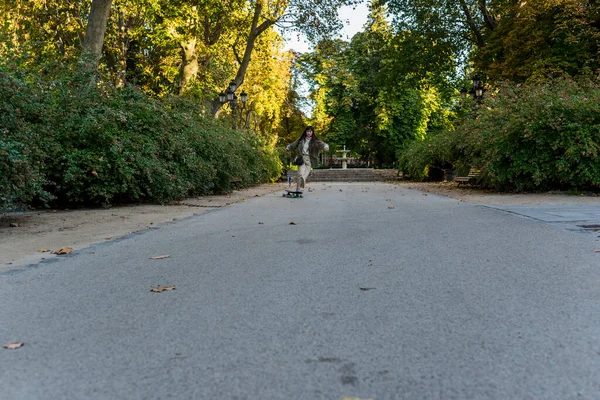 Genç kaykaycı kadın parkta sörf tahtası ile numara yapıyor. Hobi ve spor konsepti.
