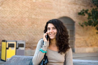Woman smiling while talking on the phone outdoors. Technology concept.