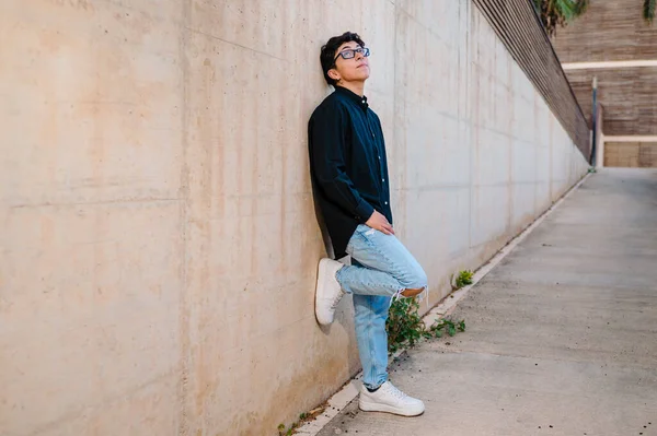 stock image Confident transgender person in glasses looking at the camera while posing standing outdoors on a walkway.