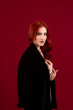 Ayrı bir arkaplanda poz verirken kameraya bakan şık bir kadın..