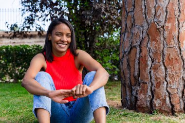 Mutlu anne çimlerin üzerinde oturuyor, dışarıda parkta eğleniyor. Anneler Günü.