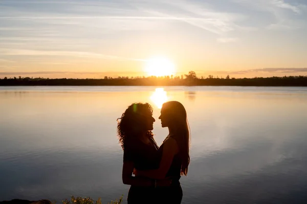 Pareja Lesbianas Mirándose Abrazándose Mientras Están Pie Junto Lago Atardecer —  Fotos de Stock