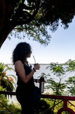 Turist kadın dışarıda gezerken eşini içiyor. Seyahat konsepti. Siluet