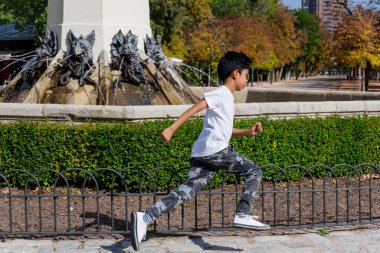 Genç bir çocuk parkta çocuk parkında koşarken eğleniyor. Çocukluk kavramı.