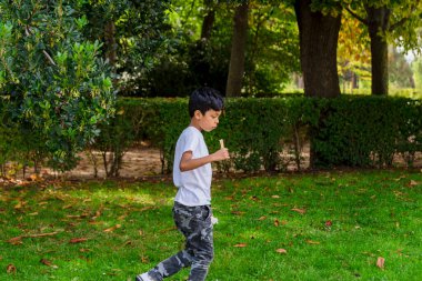 Genç bir çocuk parkta çocuk parkında koşarken eğleniyor. Çocukluk kavramı.