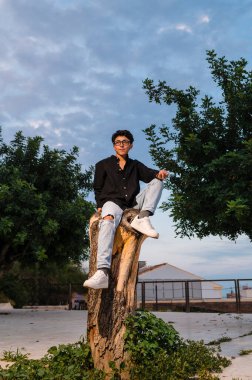 Açık havada poz verirken kameraya bakan gözlüklü bir transseksüel. Dikey resim.