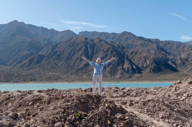 Bir dağ manzarasında doğanın tadını çıkarırken kollarını açmış bir adam. Seyahat ve turizm kavramı.