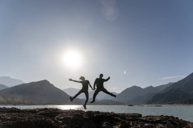 Çiftler, doğal dağ ve göl manzarasıyla dışarı atlarken poz veriyorlar. Doğa ve seyahat kavramı.