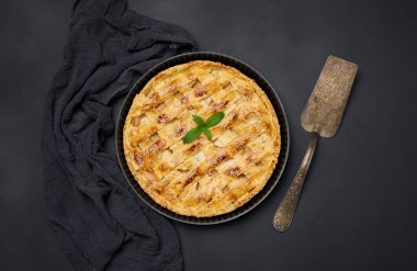 Round baked apple pie on a black table. View from above