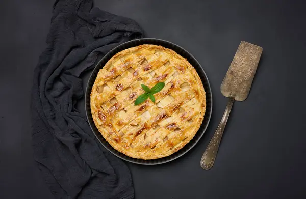 Round baked apple pie on a black table. View from above