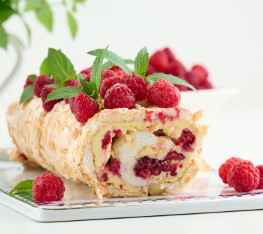 Baked meringue roll with cream and fresh red raspberry, white background