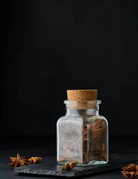 stock image Dry star anise in a transparent glass bottle on a black background