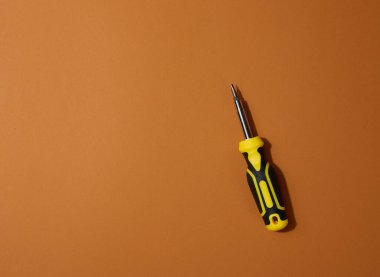 Kahverengi arka planda kauçuk saplı tornavida, kapat. Boşluğu kopyala