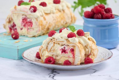 Baked meringue roll with cream and fresh red raspberry, white background	