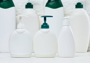 Beyaz bir rafta sıvı ürünler için pompası olan beyaz plastik bir kap. Kozmetik, sabun, krem için kap