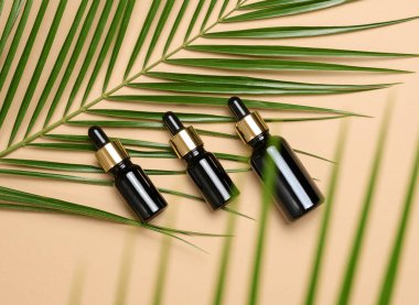 Kahverengi arka planda pipeti olan cam kahverengi kozmetik şişeler, üst manzara. Sıvı ürünler için kaplar