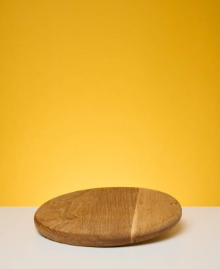 Sarı arka planda yuvarlak ahşap mutfak pizza tahtası. Boşluğu kopyala