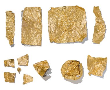 Beyaz izole bir zemin üzerinde altın folyo parçaları, üst görünüm