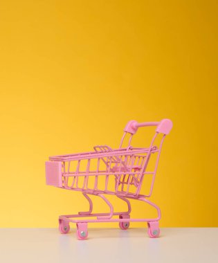 Mavi arka planda boş bir minyatür alışveriş arabası. Mevsimlik satış