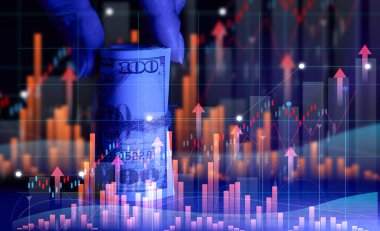 Hand holds a roll of one hundred dollar bills tied with a rope and a graph with rising rates. Income growth concept, high margin, profitable business