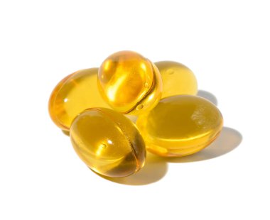 Yellow capsules with fish oil on a white background, close up