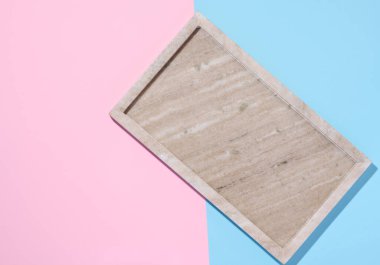 Empty beige rectangular marble plate on a blue pink background, top view