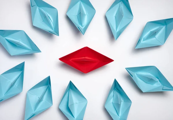 A group of blue paper boats surrounded one red boat, the concept of bullying, search for compromise. Top vie