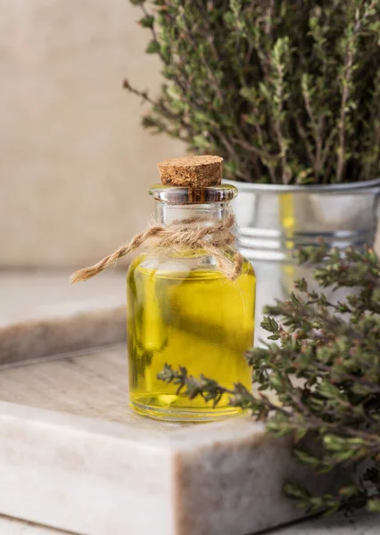 Thyme essential oil and fresh thyme sprigs on table, ingredient for cosmetics and cuisin