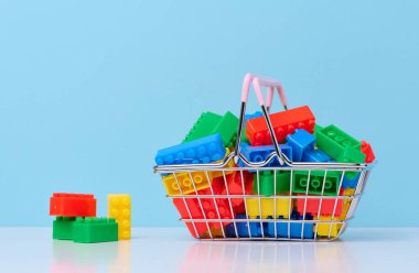 Plastic colorful building blocks in a miniature metal shopping cart, educational game for children 