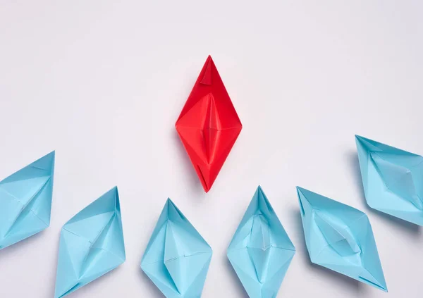 A group of blue paper boats surrounded one red boat, the concept of bullying, search for compromise. Top view