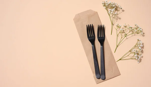 米色背景的塑料黑色叉子 一次性野餐用品 顶视图 — 图库照片
