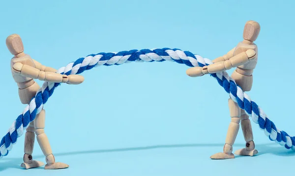 Two wooden mannequins are pulling a rope, concept of a strong leader in business