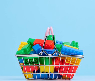 Plastic colorful building blocks in a miniature metal shopping cart, educational game for children 