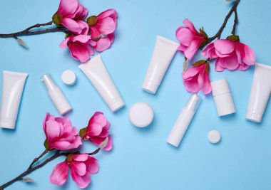 Mavi arka planda kozmetik ürünleri için beyaz plastik tüpler, kavanozlar ve kaplar, ürünlerin reklam ve markalaşması, düz yatış