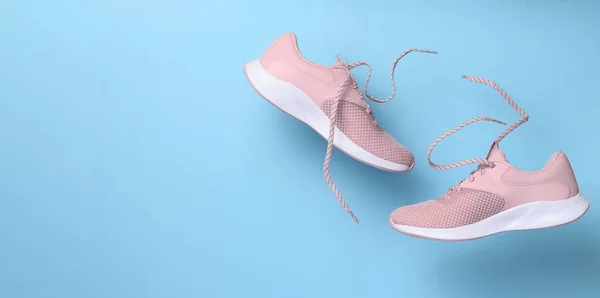 粉色女运动鞋 鞋带在蓝色的背景上飘扬 复制空间 — 图库照片