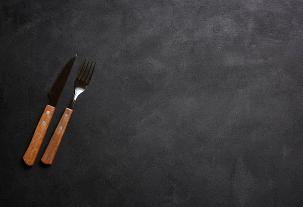 黒い背景に木製のハンドル付きフォークとナイフ トップビュー — ストック写真