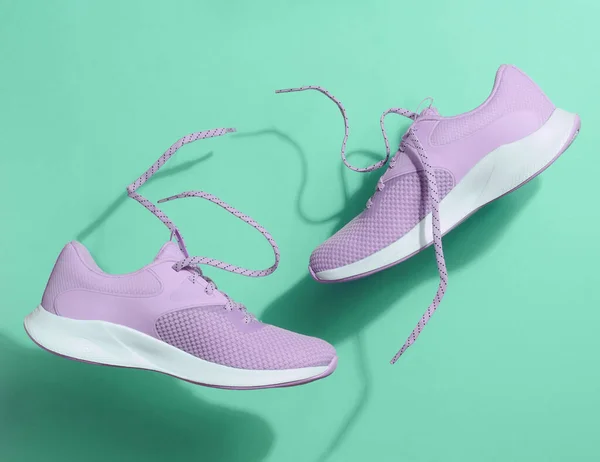 紫色女子运动鞋 鞋带在绿色背景上飘扬 — 图库照片