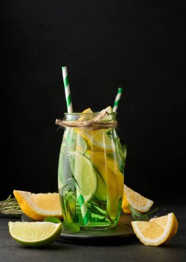 Limon, limon, biberiye filizi ve nane yapraklı şeffaf bardakta limonata.