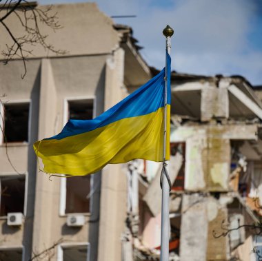 Ukrayna 'da yıkılmış bir binanın arka planında Ukrayna bayrağı var. Bina bir Rus hava bombasıyla yıkıldı.