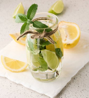 Limon, limon, biberiye filizi ve nane yapraklı şeffaf bardakta limonata.