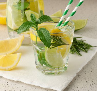 Limon, limon, biberiye filizi ve nane yapraklı şeffaf bardakta limonata.