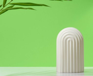 Beyaz dekoratif kemer, palmiye yaprağı ve gölgesi olan soyut yeşil arkaplan, sergi ürünleri, kozmetik ürünleri için sahne