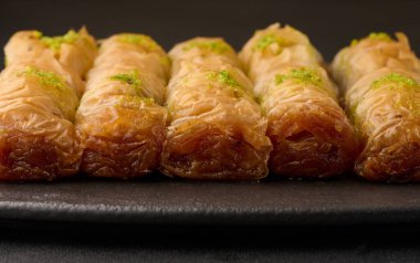 Balın içinde fırınlanmış baklava parçaları ve kara tahtaya serpiştirilmiş şam fıstığı.