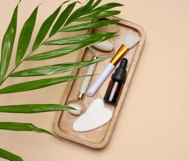 Pipetli cam şişeler, ahşap tezgahta taş bir yüz masaj aleti, üst manzara.