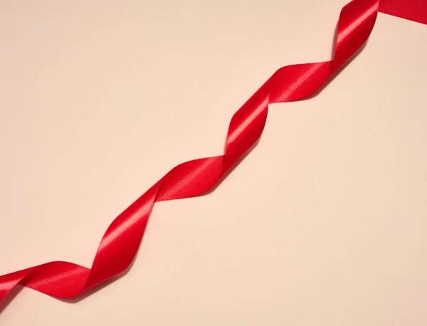 Stock image Red silk ribbon on a beige background, top view