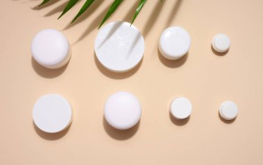 Bej bir arka planda kozmetik için beyaz kavanoz. Krem, jel, serum, reklam ve ürün tanıtımı için ambalaj