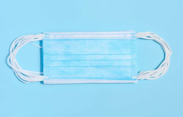 Wegwerp Blauw Medisch Gezichtsmasker Tegen Virusbescherming Een Blauwe Achtergrond Bovenaanzicht — Stockfoto