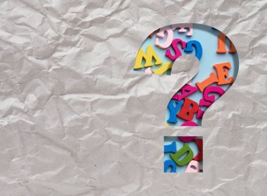 Kırışmış gri kağıtta soru işareti, içinde ahşap harfler.