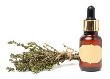 Üzerinde pipet olan cam kahverengi bir şişe ve beyaz izole bir arka planda bir kimyon dalı, yağlar ve esanslar için bir kap.